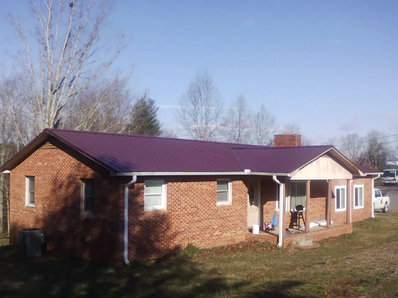 Burgundy metal roof on a brick ranch home with a new addition in Wolcottville