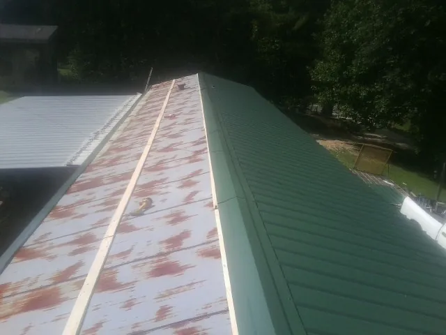 Old rusted panels beside newly installed green metal roofing — Wind Damage Roof Repair by Roofing Brothers in Wolcottville