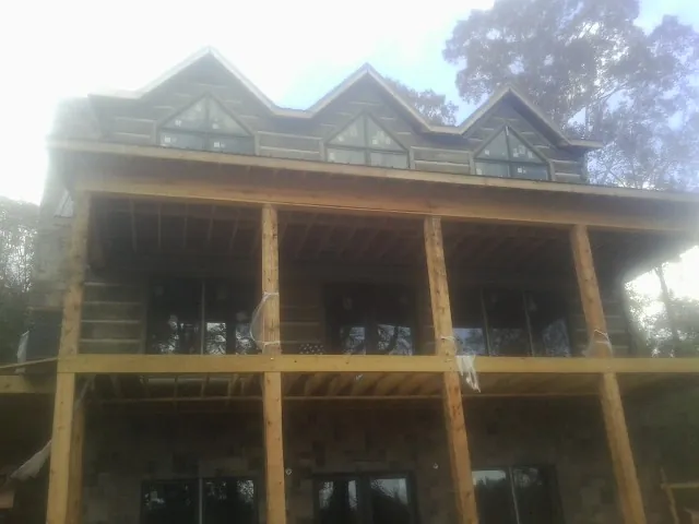 Dormers and porch framing on a large log home under construction — Roof Coating work by our crew in Wolcottville