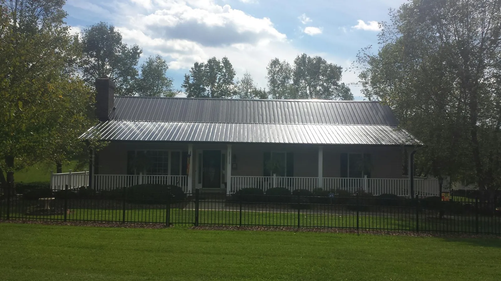 Gray metal roof on a brick ranch with a full width front porch — Gutter Guard Installation work by our crew in Wolcottville