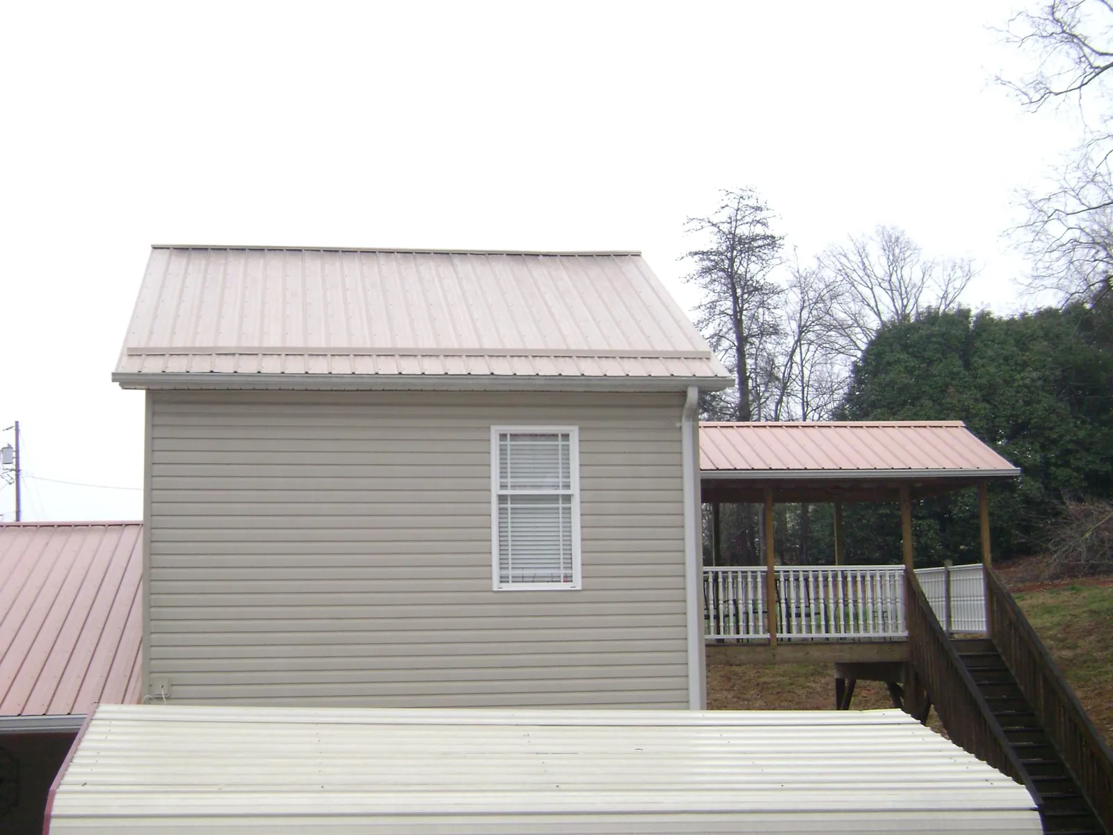 Tan metal roofs on a two story addition and attached porch, from a Roof Replacement job in Wolcottville