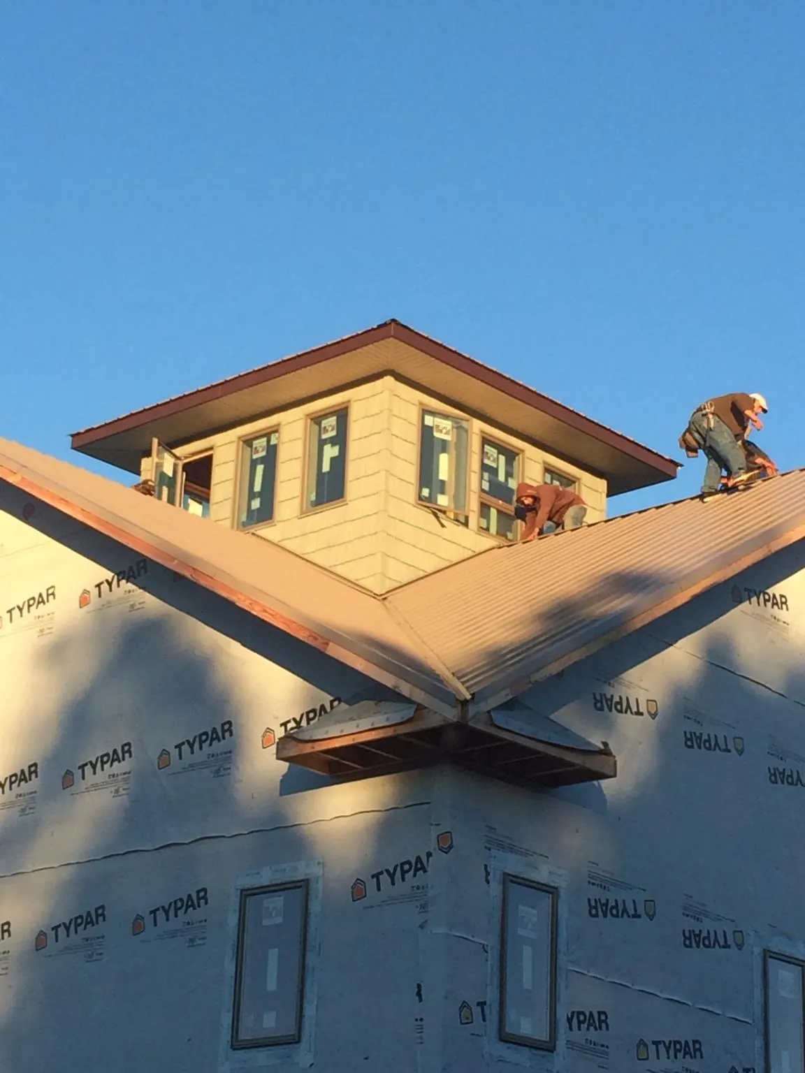 Roofers working around a rooftop cupola on a new metal roof at sunset — Roof Waterproofing in Wolcottville by Roofing Brothers